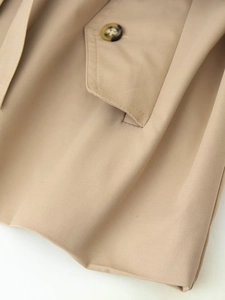 Detailed macro view of beige trench coat twill fabric with tortoise shell button