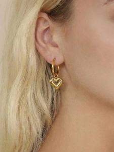 Close-up of a model wearing a 18k gold plated heart charm earring with a polished finish