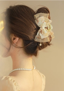 Detail of elegant bow hair claw with pearl pendant and golden leaf accent