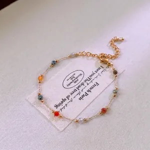 Minimalist gold chain bracelet with colorful beads and lobster clasp on white card