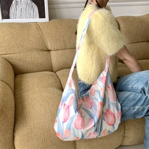 Detailed view of pink tulip floral canvas bag worn by a model in a cozy indoor setting