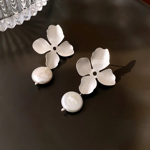 Sliver brushed metal flower earrings with freshwater pearls on a dark reflective surface