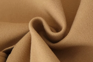Close-up of premium camel wool fabric texture with soft folds on a loose-fit coat