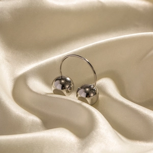 Close-up of dual stainless steel spheres on a ring over soft beige silk fabric