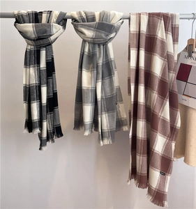 Detail view of plaid cashmere scarf featuring soft tassels and classic checkered patterns