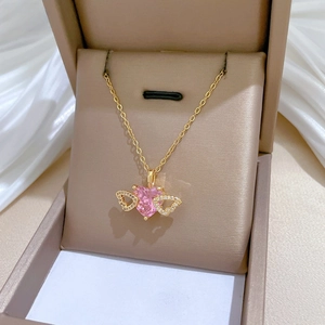 Close-up of heart-shaped pink stone pendant with pavé wings on a gold chain necklace