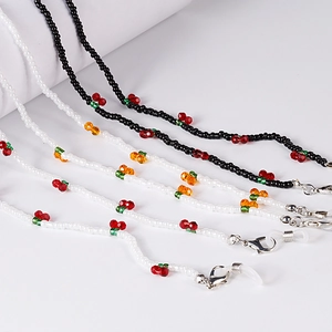 Detail of beaded fruit chains featuring red cherries and secure metal lobster clasps