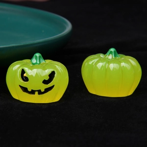 Macro shot of 3D luminous resin pumpkins with jack-o'-lantern face on black background