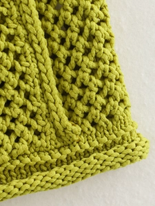 Detalle de top sin mangas de punto grueso verde hierba con texturas de ganchillo