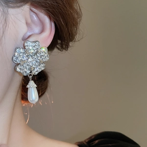 Close-up of floral diamond earring with a teardrop pearl drop on a model