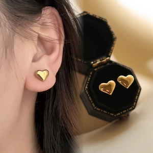 Detail of 18K gold heart earring on ear model and in a black jewelry gift box