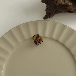 Macro shot of a dark tortoiseshell acetate hair claw on a beige ceramic plate background