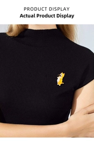 Detailed view of an orange enamel cat brooch with a fish on a black knitted sweater