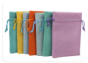 Close-up of seven colorful linen drawstring jewelry pouches in various pastel shades