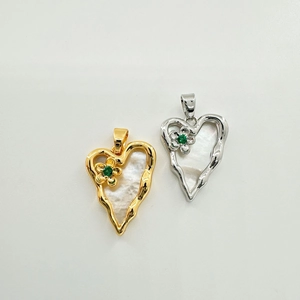 Macro shot of heart charms with mother of pearl inlay and green zircon flower detail