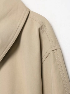 Close-up of khaki trench coat collar with detailed stitching on twill fabric
