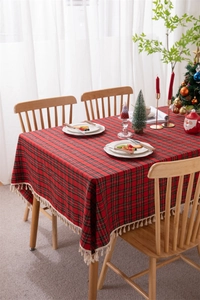 Macro detail of red and green plaid Christmas tablecloth with decorative beige tassels
