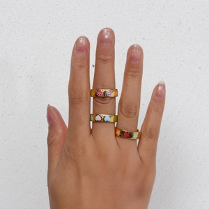 Close-up of gold stainless steel rings with colorful smiley, heart, and star patterns
