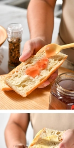 Detailed view of a yellow silicone spatula spreading red fruit jam on sliced bread