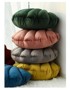 Detailed view of stacked velvet shell-shaped cushions in green, pink, gray, and yellow