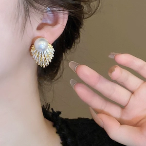 Close-up of pearl stud earrings with fan-shaped gold leaves and sparkling crystals