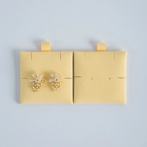 Macro detail of gold flower earrings with white pearls on yellow velvet display cards