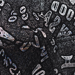 Close-up of black baseball cap with holographic silver glitter and letter pattern detail