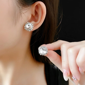 Detail shot of silver square earrings with a large central crystal and diamond halo