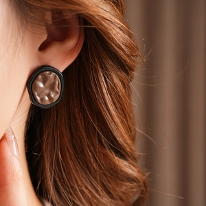 Macro view of geometric resin earrings with brown wavy texture and black hexagonal frames