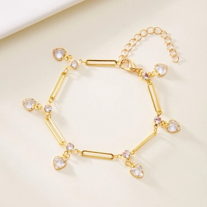 Detail view of golden paperclip chain bracelet with heart crystals and sparkling stones