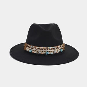 Detalle de sombrero fedora negro de lana con banda trenzada, estrella de mar y concha