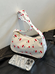 Detail of white nylon shoulder bag with red cherry prints on a black leather jacket