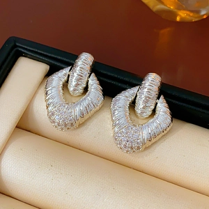 Macro shot of silver horseshoe earrings with diamond-cut texture and cubic zirconia