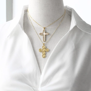 Primer plano de collares dorados en capas con colgante de cruz y medalla religiosa