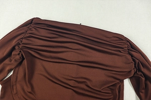 Detailed view of the pleated neckline and gathered fabric on a dark brown bodysuit