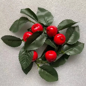 Close-up of a mini Christmas wreath with red berries and green leaves on white background