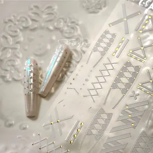 Macro shot of pearl white and metallic 3D nail stickers with geometric line patterns