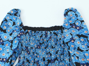Detail eines blauen Blumenkleides mit gesmoktem Karree-Ausschnitt und gerafftem Stoff