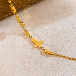 Gros plan d'un bracelet en acier titane doré avec pendentif papillon et perles mates