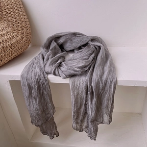 Detail shot of a grey vintage pleated silk scarf draped on a white minimalist shelf
