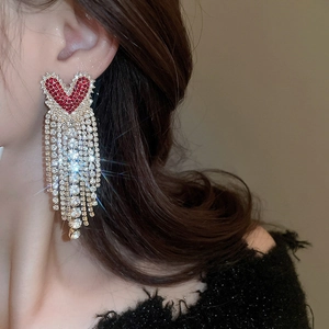 Close-up of red heart tassel earrings with sparkling rhinestones and golden base