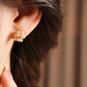 Gros plan d'une boucle d'oreille fleurie en perles et diamants portée par un mannequin