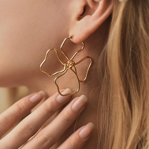 Chic 18K gold plated brass earrings featuring hollow floral asymmetric design on model