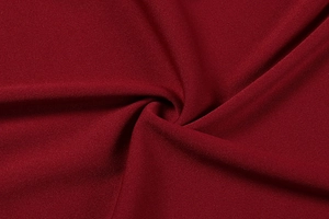 Close-up detail of burgundy red fabric showing high-density knit texture and soft folds