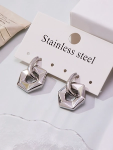 Macro detail of geometric hexagonal pendant earrings in polished stainless steel finish