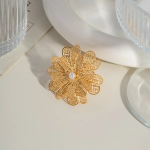 Close-up of golden hollow camellia flower ring with center pearl on white tray