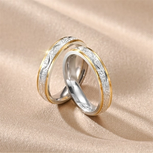 Detailed close-up of two-tone titanium steel couple rings with frosted finish on silk