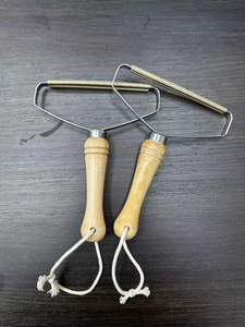 Detail of two portable manual lint removers with wooden handles and copper blades for coats