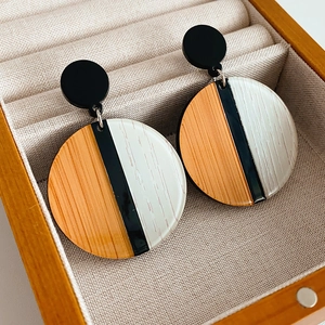 Gros plan de boucles d'oreilles rondes avec motifs de grain de bois noir, orange et blanc