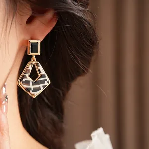 Elegant geometric resin rhombus earrings with golden frames and black stone accents